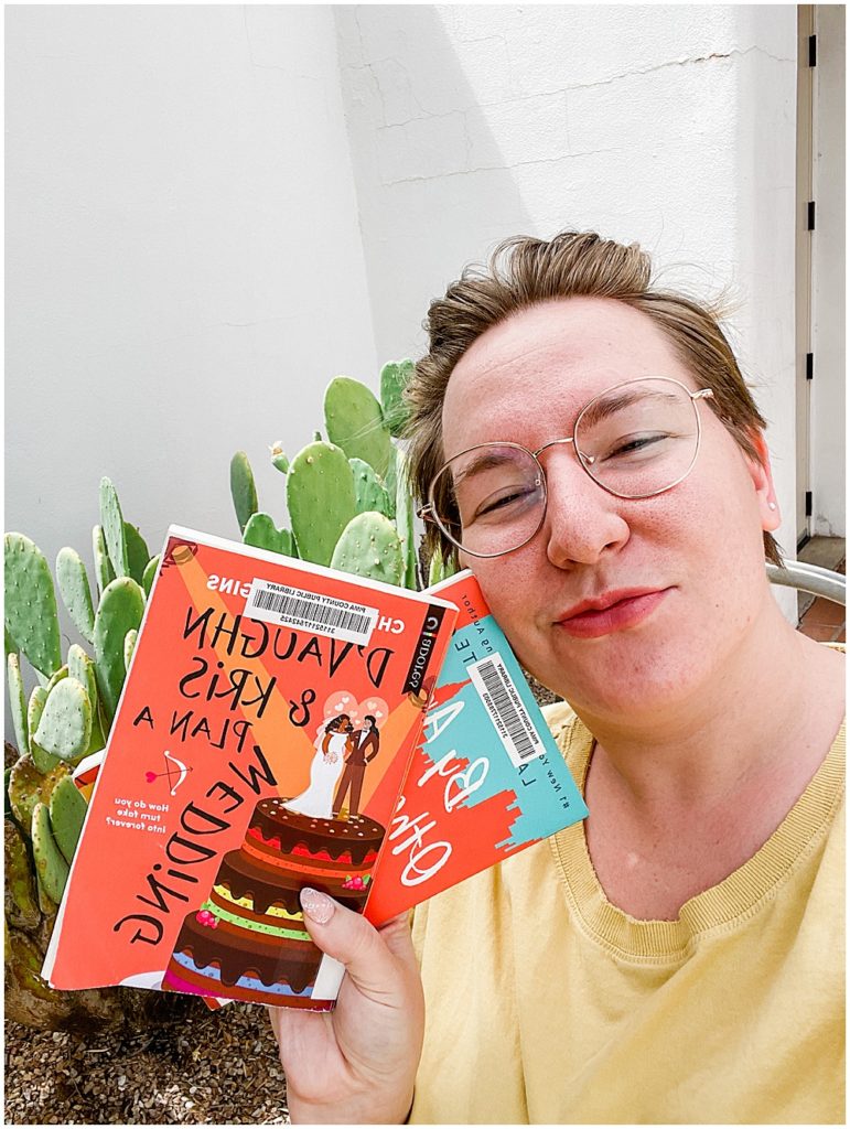 queer book recommendations - holding two books outside the library