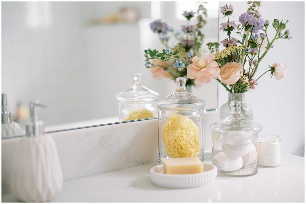 at home spa night bathroom countertop with flowers, bath bombs, and scrubs 