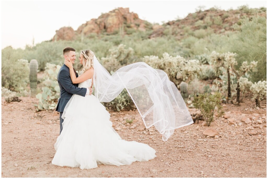should you wear a veil? Photo of a couple on their wedding day with the bride's veil blowing in the wind 