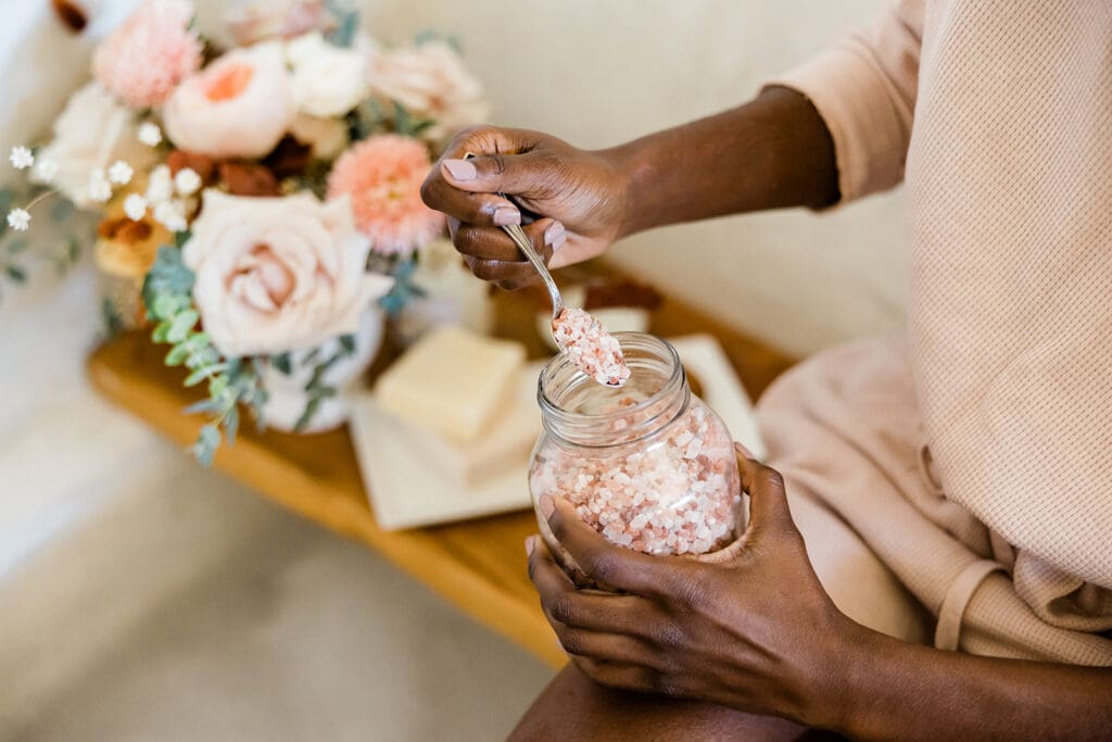 little pleasures to indulge in while preparing for egg retreival with ivf - a Black woman taking a bubble bath with bath salts and fresh flowers 